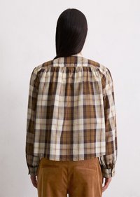 Brown and cream plaid blouse with a gathered back, long sleeves, and button cuffs, made of lightweight fabric with a soft texture.