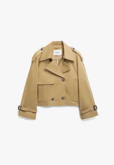 Lühendatud, kahvatu trenss, mis on valmistatud siledast kangast, millel on topelt-kliendi eest ja suured nööbid, eemaldatavad õlavarreklapid ning vöödega mansetid.