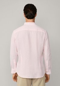 Camisa de manga larga de color rosa claro, hecha de lino, con cuello y puños abotonados. Tejido suave y texturizado con un corte relajado.