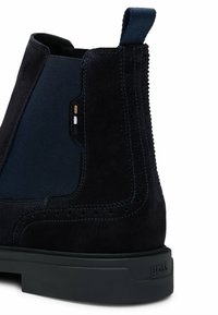 Navy suede nilkkurit elastisilla sivupaneeleilla, huomaamaton reikäkuviointi ja musta kumipohja. Mukana vetoketju helpottamaan pukemista.