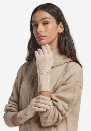 Guanti beige in maglia con polsini a costine, caratterizzati da un design scintillante di perline sul dorso e una etichetta sul polso. Materiale morbido e strutturato.