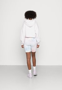 Sweatshirt blanc coupé, short de vélo pastel tie-dye, et baskets montantes violettes claires. Comprend des manches longues et une coupe décontractée.