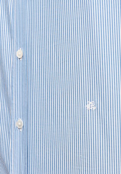 Blå og hvide stribet skjorte med knapper i let bomuldsstof, der har en lille hvid broderet logo nær placket.