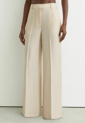 Beige højtaljede bukser med brede ben, tynde lodrette sorte nålestriber og bæltestropper, båret af en person mod en ensfarvet baggrund.