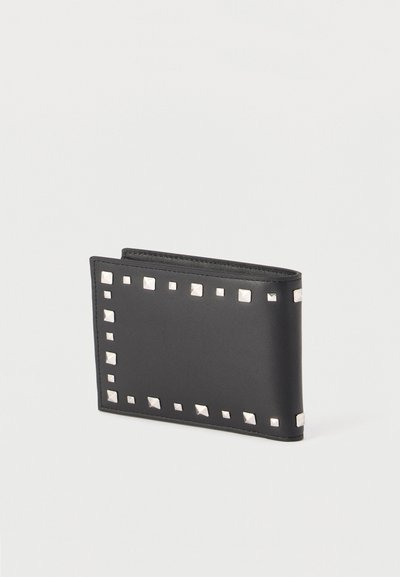 Μαύρο δερμάτινο πορτοφόλι με ασημένιες τετράγωνες τρουκς τοποθετημένες ομοιόμορφα κατά μήκος των άκρων, διπλωμένο κλειστό πάνω σε απλό ανοιχτό φόντο.