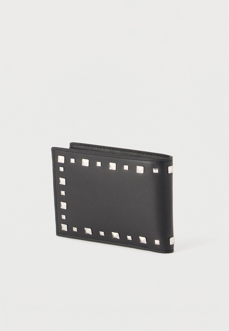 Portefeuille en cuir noir avec des clous carrés en argent espacés uniformément le long des bords, plié fermé sur un fond clair uni.