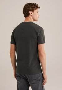 Sötét szürke, rövid ujjú póló, kerek nyakkal, puha, sima anyagból készült, amelyet hátulról mutat be egy férfi modell.