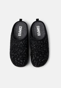 Zapatillas de felpa negra con un acabado texturizado, que cuentan con un forro suave y una forma redondeada. El interior muestra el logo "CAMPER".