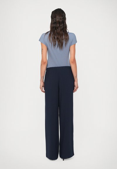 Calças largas azul-marinho com um cinto elástico macio, combinadas com uma blusa de manga curta azul-claro com uma textura simples e suave.