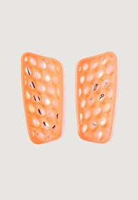 Dos espinilleras protectoras naranjas con un diseño ventilado de panal, fabricadas con material ligero, que presentan bordes redondeados y marcas de tamaño visibles.