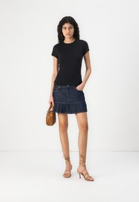 Zwarte fitted t-shirt, blauwe denim rok met ruches, beige sandalen met bandjes en een bruine handtas. Eenvoudig ontwerp, casual stijl, zachte textuur.