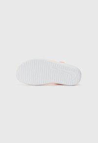 White sneaker sole with light pink accents, featuring a textured rubber surface and horizontal ridges along the bottom for grip.