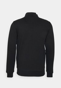 Sweat-shirt noir à manches longues avec poignets, ourlet côtelés et col haut, vu de dos sur un fond clair.