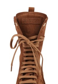 Botte montante en daim marron avec des lacets plats noués en nœud et une étiquette BRONX embossée sur la languette intérieure.