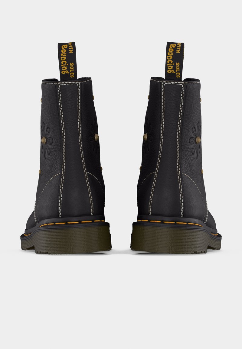 Bottes courtes en cuir noir avec embossage floral, coutures jaunes et languettes de tirage "With Bouncing Soles", vues de dos.