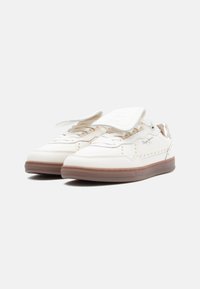 Valged vabaajajalatsid, millel on perforatsioonidega disain, tasased tallad ja reguleeritav rihm. Omapärased läikivad aktsendid ja peened brändielemendid külgedel.