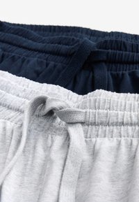 Zwei Hosen mit elastischem Bund, eine hellgrau und eine dunkelblau, jeweils mit gebundenem Kordelzug vorne.