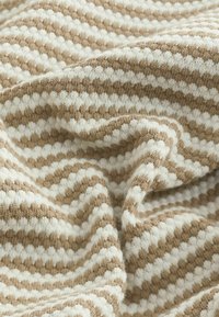 Strickstoff mit abwechselnd braunen und weißen Streifen in einem strukturierten Muster, das ein welliges Aussehen mit weichen, gemütlichen Fasern erzeugt.