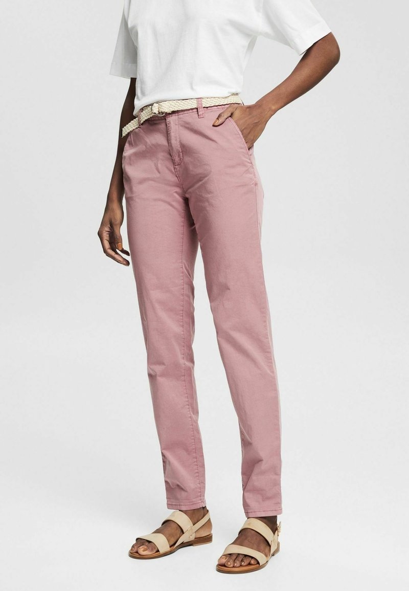 Pantalon en coton rose clair avec une coupe droite, doté d'une ceinture tissée beige. Assorti à un t-shirt blanc uni et des sandales beiges.