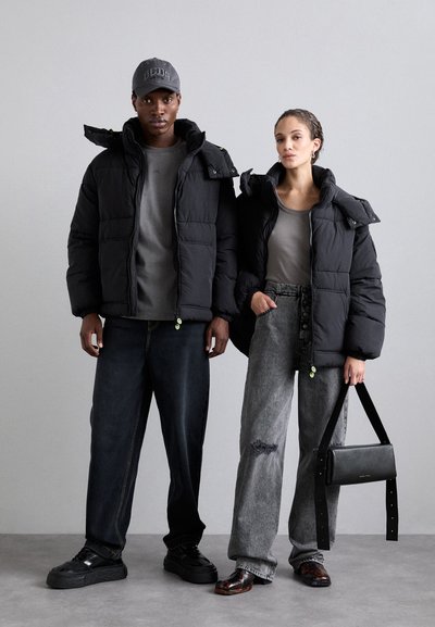 Black puffer jackets with high collars, gray t-shirts, dark denim and gray pants, black shoes, and a small black handbag.