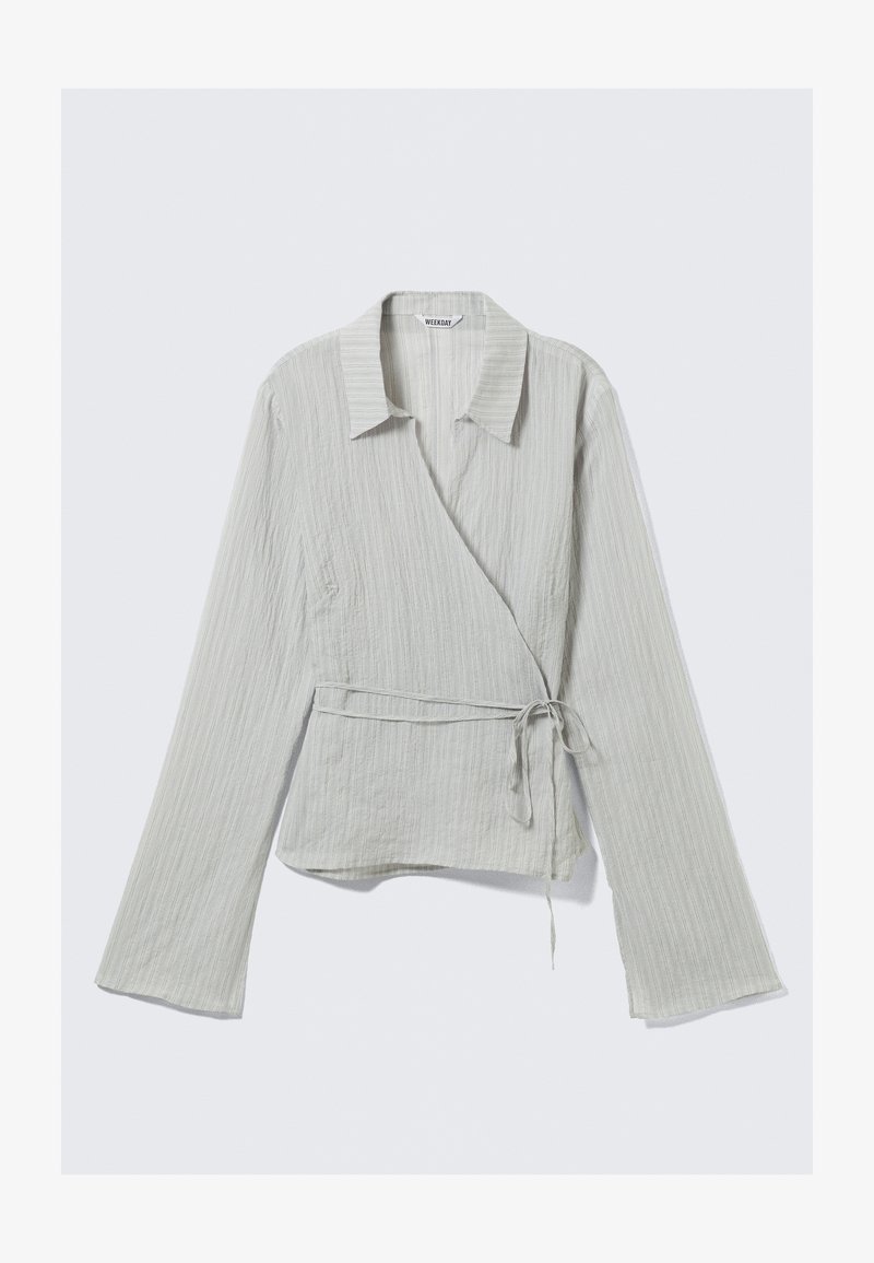 Haut cache-cœur gris clair à manches longues, rayures verticales, col à revers et lien à la taille. Confectionné dans un tissu doux et texturé.