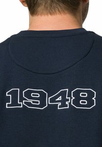 Granatowa bluza z okrągłym dekoltem i białym haftowanym napisem "1948" na plecach. Materiał wydaje się miękki o gładkiej fakturze.