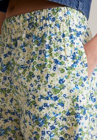 Floral shorts in light fabric featuring a yellow background with blue and green abstract patterns. Elastic waistband and side pockets.