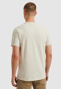T-shirt à manches courtes de couleur crème, en coton léger, col rond. Texture lisse, sans motifs ni accents visibles.