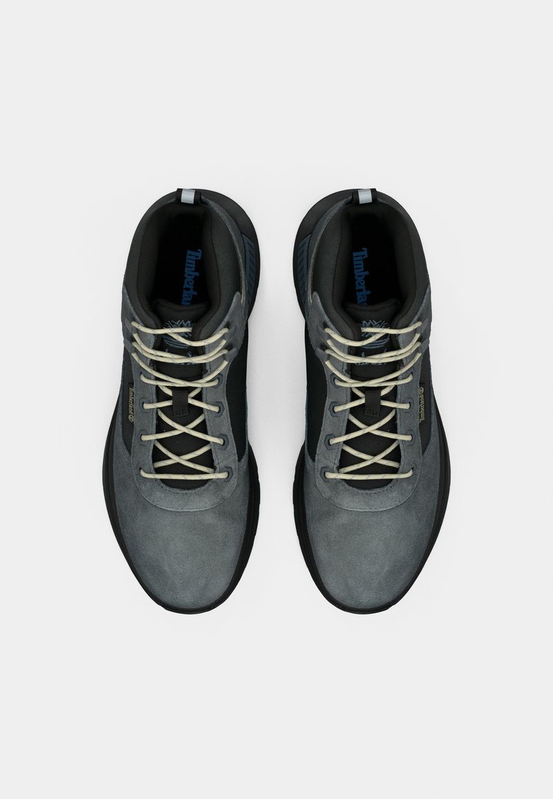 Pair of gray and black Timberland sneakers with white laces, viewed from above on a white background.