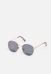 Gafas de sol redondas con lentes gris oscuro, montura de patrón carey y delgadas varillas de metal dorado. Almohadillas nasales transparentes adjuntas.