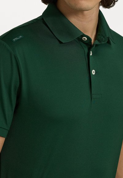 Zaļš polo krekls, izgatavots no gludas auduma. Tam ir klasisks apkakle, trīs pogu aizdare un RLX logo kreisajā plecā.