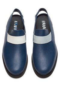 Paire d'escarpins slingback en cuir bleu marine avec larges brides blanches et semelles noires, vus de dessus.
