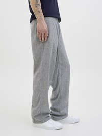 Stripete, lette bukser i grått og hvitt, med en avslappet passform og subtil tekstur, sammen med hvite sneakers.