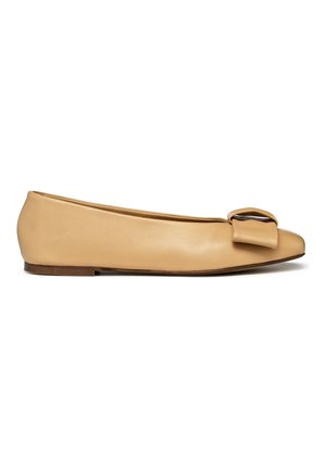 Chaussure plate en cuir tan avec un bout pointu et un accent en nœud sur le dessus. Présente un profil bas et une petite semelle en bois.