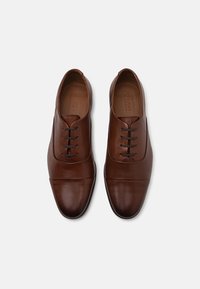 Chaussures habillées en cuir marron avec une finition lisse, bout rond et cinq œillets pour les lacets ; présente un design discret de bout droit.