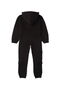 Mono negro con capucha que presenta un top corto, puños elásticos y bolsillos tipo cargo en los pantalones. Fabricado con un tejido suave y texturizado.