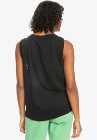 Haut noir sans manches avec une coupe décontractée, présentant un col rond et un léger détail ruche au dos. Tissu lisse et léger.