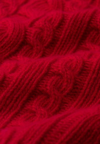 Raudona megzta medžiaga, su kabelių raštu ir iškilniu tekstūra, pagaminta iš minkštos vilnos arba akrilo.