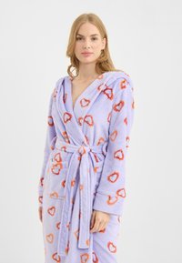 Paarse fleece badjas met hartpatronen in oranje en rood, voorzien van een capuchon, lange mouwen en een bindriem in de taille.