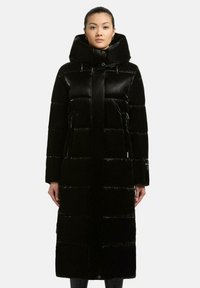 Cappotto lungo nera imbottito con finitura lucida, colletto alto e tasche con zip. Presenta cuciture orizzontali e una silhouette dritta.