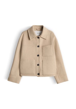 Beige wollen jas met een kraag, knoopsluiting aan de voorkant en twee borstzakken. Heeft een vierkante pasvorm en lange mouwen.