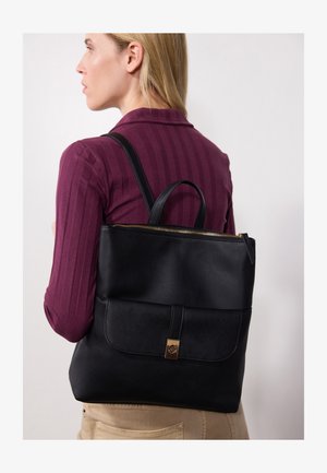 Sac fourre-tout en cuir noir avec un design structuré, doté d'une fermeture éclair et d'une poche à rabat à l'avant avec un fermoir doré.