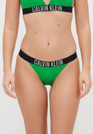 Grön bikinitopp med V-ringning och matchande tanga, tillverkad av ett mjukt tyg med ett svart elastiskt band som visar "CALVIN KLEIN"-logotypen.