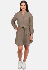 Abito camicia khaki con cintura a nastro, maniche lunghe, tessuto testurizzato e vestibilità comoda. Abbinato a sneaker bianche.