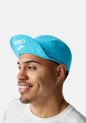 Una gorra de correr azul con visera curvada, con el logotipo "BROOKS" en blanco, hecha de tela ligera, adecuada para actividades al aire libre.