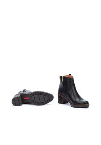 Bottines en cuir noir avec un bout rond, une fermeture éclair sur le côté et un talon empilé. La semelle présente un motif de grip texturé.