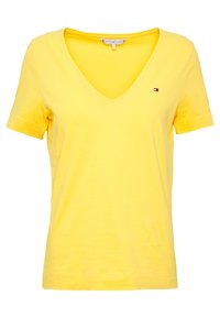 Camiseta amarilla de cuello en V, hecha de algodón suave; mangas cortas; presenta un pequeño logotipo en colores contrastantes en el área del pecho izquierdo.