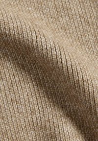 Beige gebreide stof met een geribbelde textuur, die strakke, uniforme wevingen en een zachte, warme uitstraling laat zien.