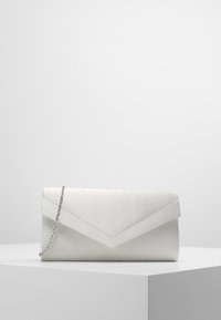 Bolso de mano de satén blanco con una cadena plateada, descansando sobre un pedestal blanco contra un fondo gris.
