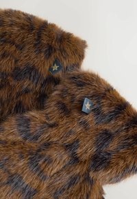 Guanti in pelliccia sintetica marrone con motivo leopardato. Presentano una superficie liscia e un'etichetta nera con un accento dorato a forma di stella.